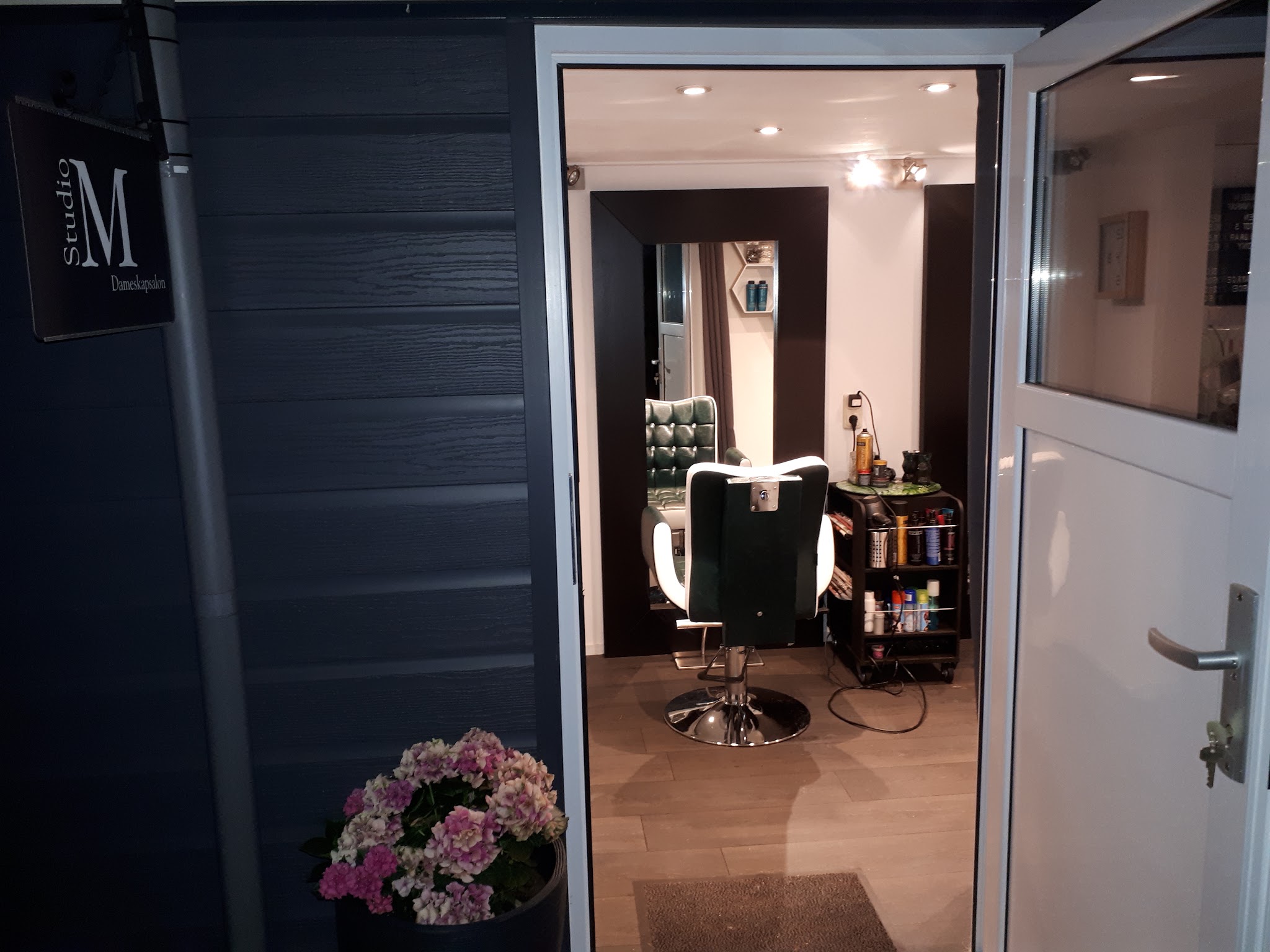 De entree van Studio M met het salonbord en de groene kappersstoel